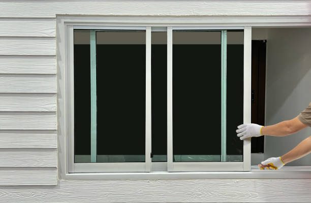 Construction worker repairing the sliding window on artificial woods siding.