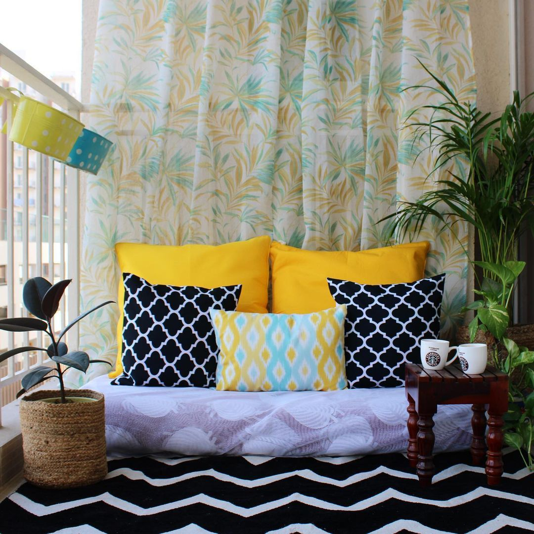 Look at how cozy this balcony looks like. It has comfortable seating, cushions, and a rug.