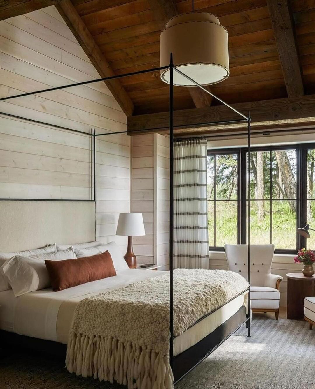 There are varied fabric materials being used in this rustic bedroom, but the most stand out are the blanket and the rug.